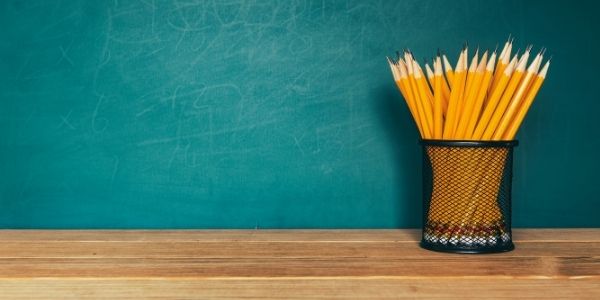 Pencils in cup in front of chalkboard